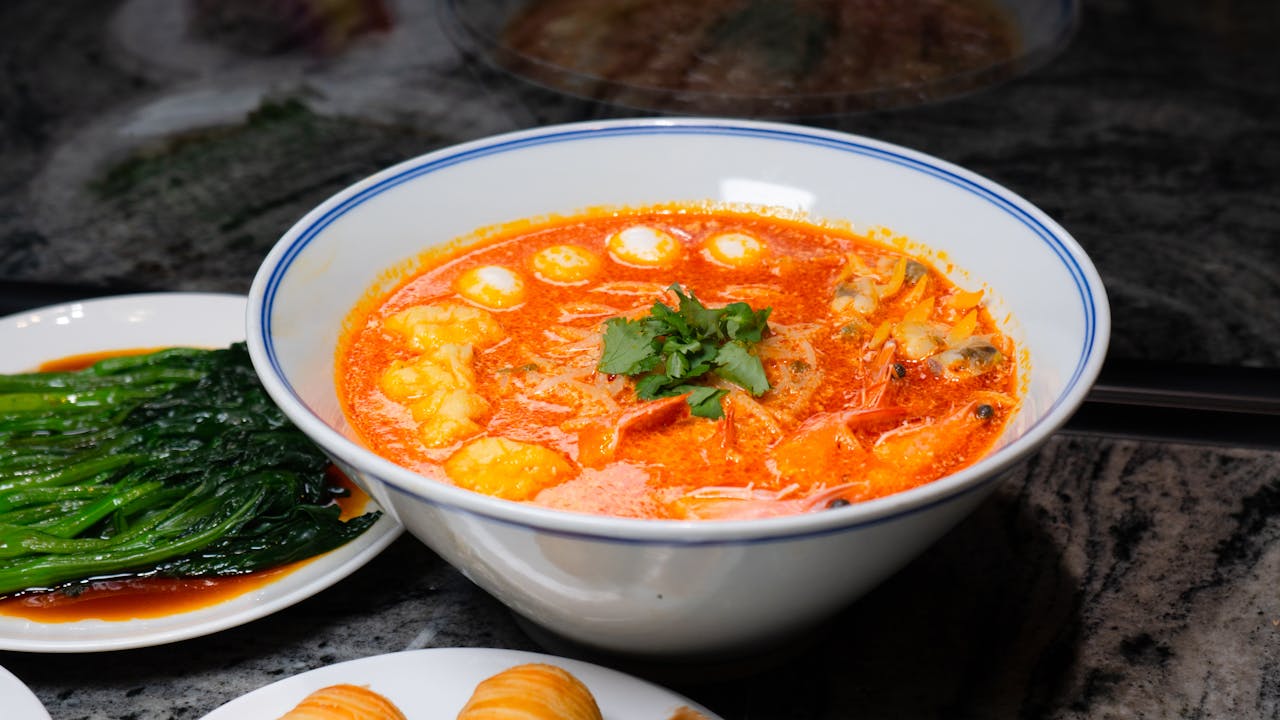 A flavorful bowl of Thai red curry soup with shrimp, garnished with fresh cilantro, captured on a dining table.