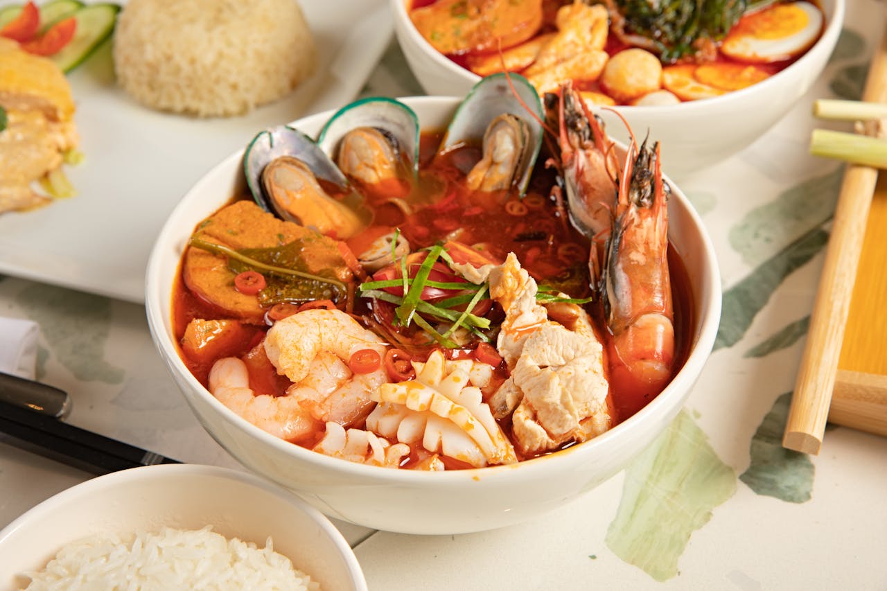 gallery-6 Flavorful seafood tom yum soup served with steamed rice, perfect for Thai cuisine lovers.