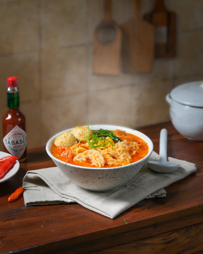 services-01 A vibrant bowl of Indonesian spicy noodle soup with fresh ingredients, perfect for a savory meal.